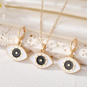 Schmuckset mit bösem Blick, Goldstern-Halskette und Ohrringen auf weißem Seidenhintergrund