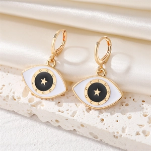 Detail der goldenen Evil Eye Ohrringe mit weißem Emaille und Sternen auf Seide