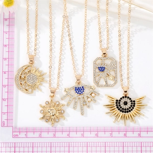 Set di collane boho dorate con pendenti a sole e luna accanto a una scala graduata