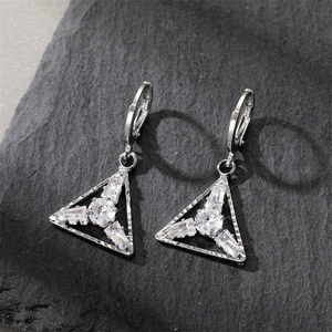 Detailed view of silver triangle drop earrings with cubic zirconia on stone background