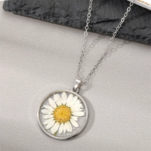 Delicate silver chain necklace featuring a white dried daisy flower in a resin pendant