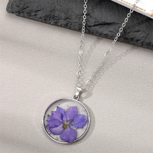 Handmade clear resin necklace with purple dried flower and silver foil on a silver chain