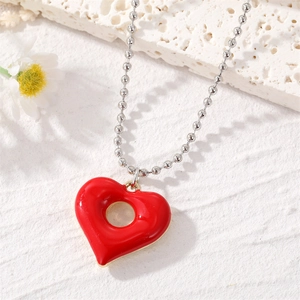 Retro red heart hollow pendant necklace with silver bead chain on white textured background