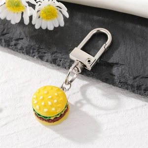 Realistic mini burger keychain with resin bread and lettuce layers on a stone background