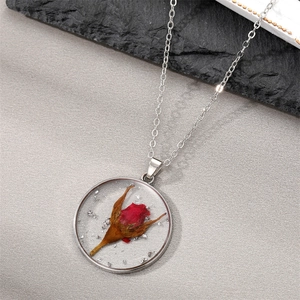 Detail of round resin pendant featuring real red dried rose buds and silver foil flakes