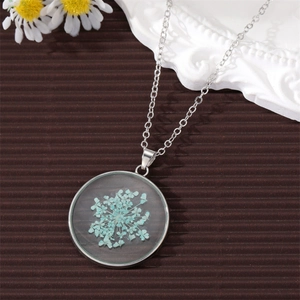 Close-up of handmade round pendant necklace with preserved light blue dried flowers