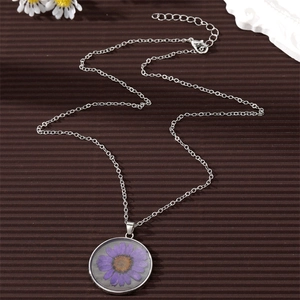 Detailed macro view of a round resin pendant featuring a real purple dried flower