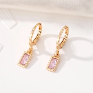 Close-up of gold-plated square pink crystal drop earrings on white textured fabric