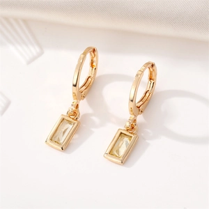 Detailed macro shot of gold square crystal drop earrings with polished rectangle pendants