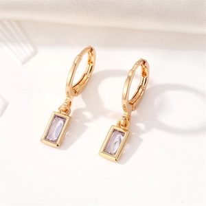 Detailed macro view of gold-plated square lavender crystal drop earrings on white fabric