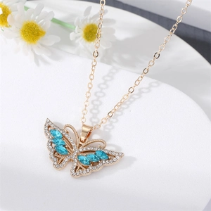 Collier pendentif papillon doré avec cristaux bleus sur un support en marbre blanc
