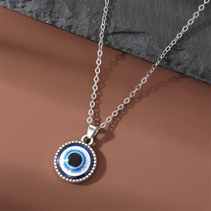 Classic silver evil eye pendant necklace with blue crystals on dark rock background
