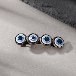 Vintage bronze evil eye hair clip featuring four blue beaded eyes in a retro styling
