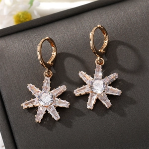 Elegante goldene Schneeflocken-Creolen mit funkelnden Zirkonia auf grauem Schmuckkästchen