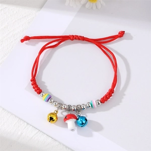 Detail view of woven red cord bracelet with colorful beads, silver bells, and mushroom charm