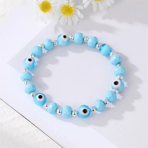 Sky blue beaded bracelet with Evil Eye charms and silver accents on white daisy background