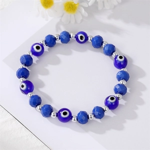 Blue Evil Eye beaded bracelet with silver metal spacers and faceted crystals on white daisy background