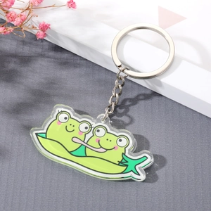 Cute green frogs in a pea pod acrylic keychain with silver metal ring on gray background