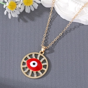 Vintage gold Evil Eye necklace with red enamel and crystals on dark texture background