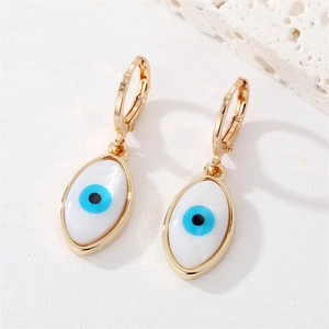 Close-up of golden evil eye hoop earrings with white shell inlay and blue pupils