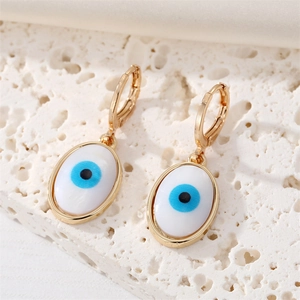 Detail of gold-plated evil eye hoop earrings with blue iris charm on white stone base