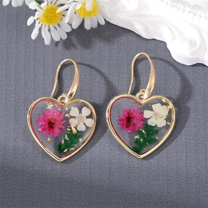 Detail shot of heart-shaped resin earrings with real dried flowers and gold foil accents