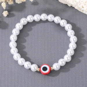 Detailed macro view of freshwater pearl bracelet with a red evil eye charm detail