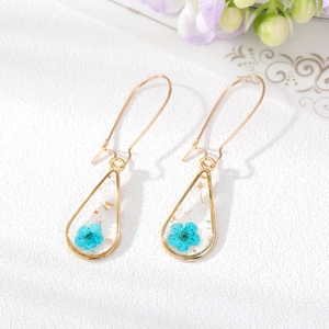 Handmade teardrop earrings with real blue dried flowers and gold foil in resin