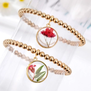 Bracciale chic con perline dorate e ciondoli in vetro con fiori secchi rossi