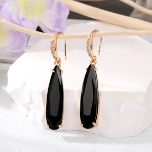 Détail de boucles d'oreilles pendantes dorées avec pierres noires sur une branche