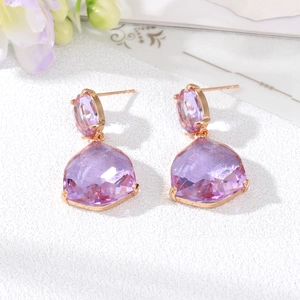 Macro detail of rose gold earrings featuring faceted violet crystals and claw setting