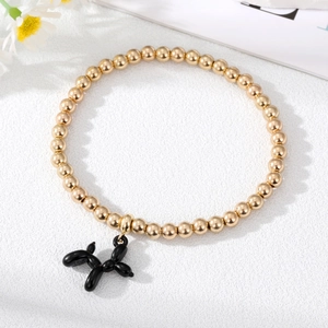 Golden beaded bracelet with a creative black balloon dog pendant on textured white background