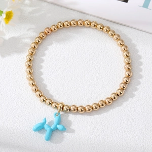 Detailed close-up of golden beaded bracelet with a blue balloon dog charm on white texture