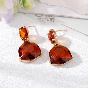 Elegant gold fan-shaped geometric earrings with amber crystal stones on a textured stand