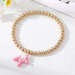 Detail of gold beaded bracelet with a pink balloon dog charm on a white background