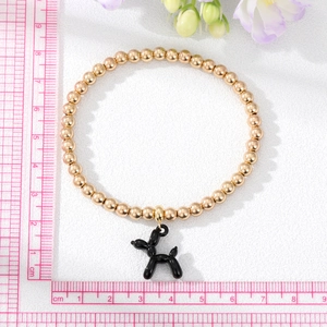 Detail view of a gold beaded elastic bracelet with a black balloon dog pendant and size measurement