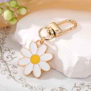 Cute daisy flower keychain with golden lobster clasp and white petals on a marble stand