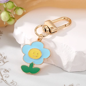 Detail of blue flower keychain with a yellow smiley face and gold-tone metal D-ring clasp