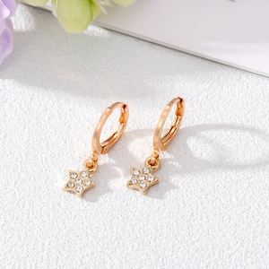Elegant gold star drop earrings with sparkling pavé crystals in a tilted studio shot