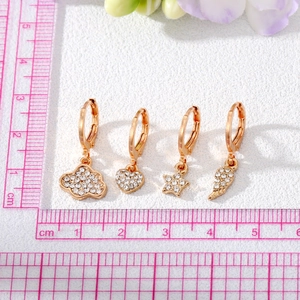 Detailed close-up of golden drop earrings with pavé crystals in heart and star shapes