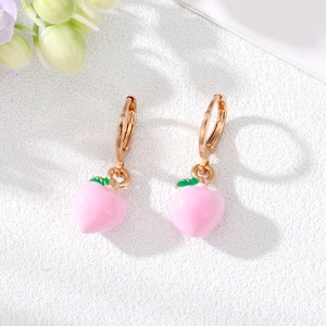 Détail de boucles d'oreilles pêche rose avec fermoir doré et petite feuille verte