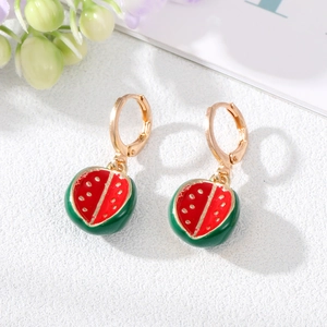 Vue macro des boucles d'oreilles pastèque plaquées or avec émail rouge et vert vibrant