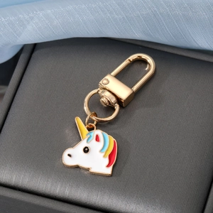 Cartoon Einhorn Metall Schlüsselanhänger mit bunter Emaille auf grauem strukturiertem Grund