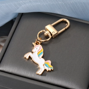Detailaufnahme eines goldenen Einhorn-Schlüsselanhängers mit Emaille auf Samthintergrund