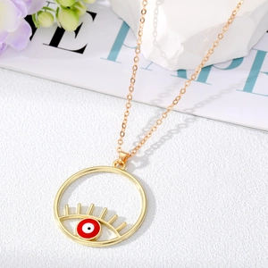 Collier doré tendance avec pendentif œil maléfique et cils sur fond de marbre