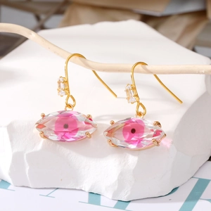 Elegantes pendientes de ojo de la suerte dorados con detalle rosa en rama de madera