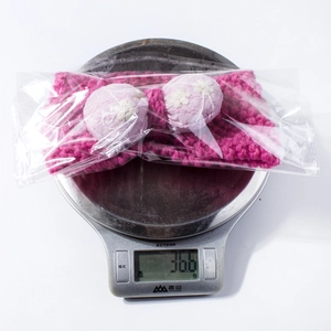 Detailed view of the rose pink knitted baby headband weighing 36.6g on a digital scale