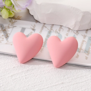 Detailed macro shot of matte pink heart earrings on minimalist aesthetic background