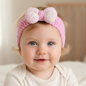 Gros plan d'un bandeau en maille rose bébé avec nœud floral brodé sur la tête d'un enfant