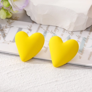Macro shot of bright yellow matte heart earrings on a vintage paper background